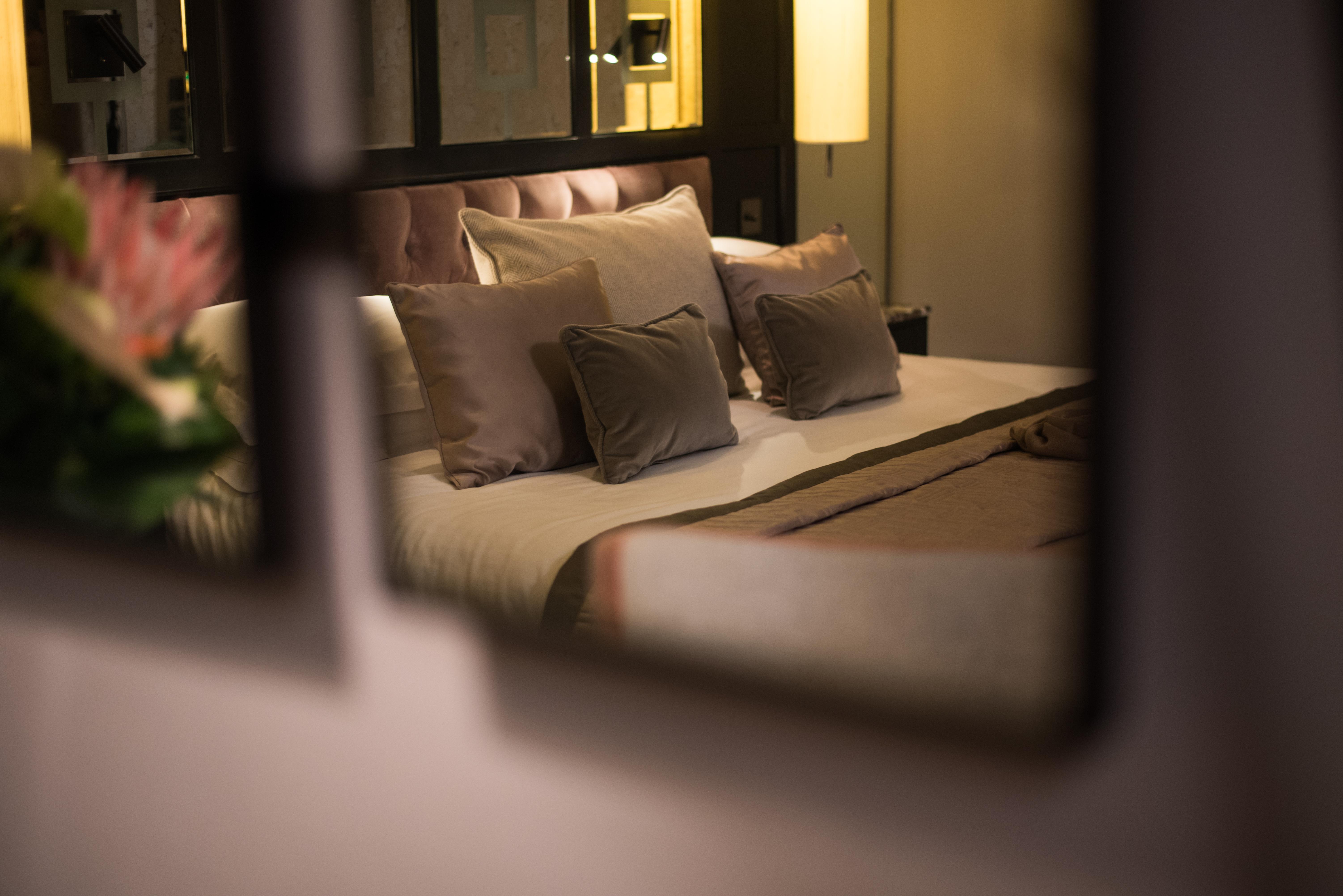 ザ フィッツウィリアム ホテル ベルファスト エクステリア 写真 The photo shows a cozy and elegantly decorated bedroom. The focal point is a plush bed with soft, neutral-colored bedding and several decorative pillows arranged neatly on it. The room has a warm ambiance, enhanced by a standing lamp that provides so