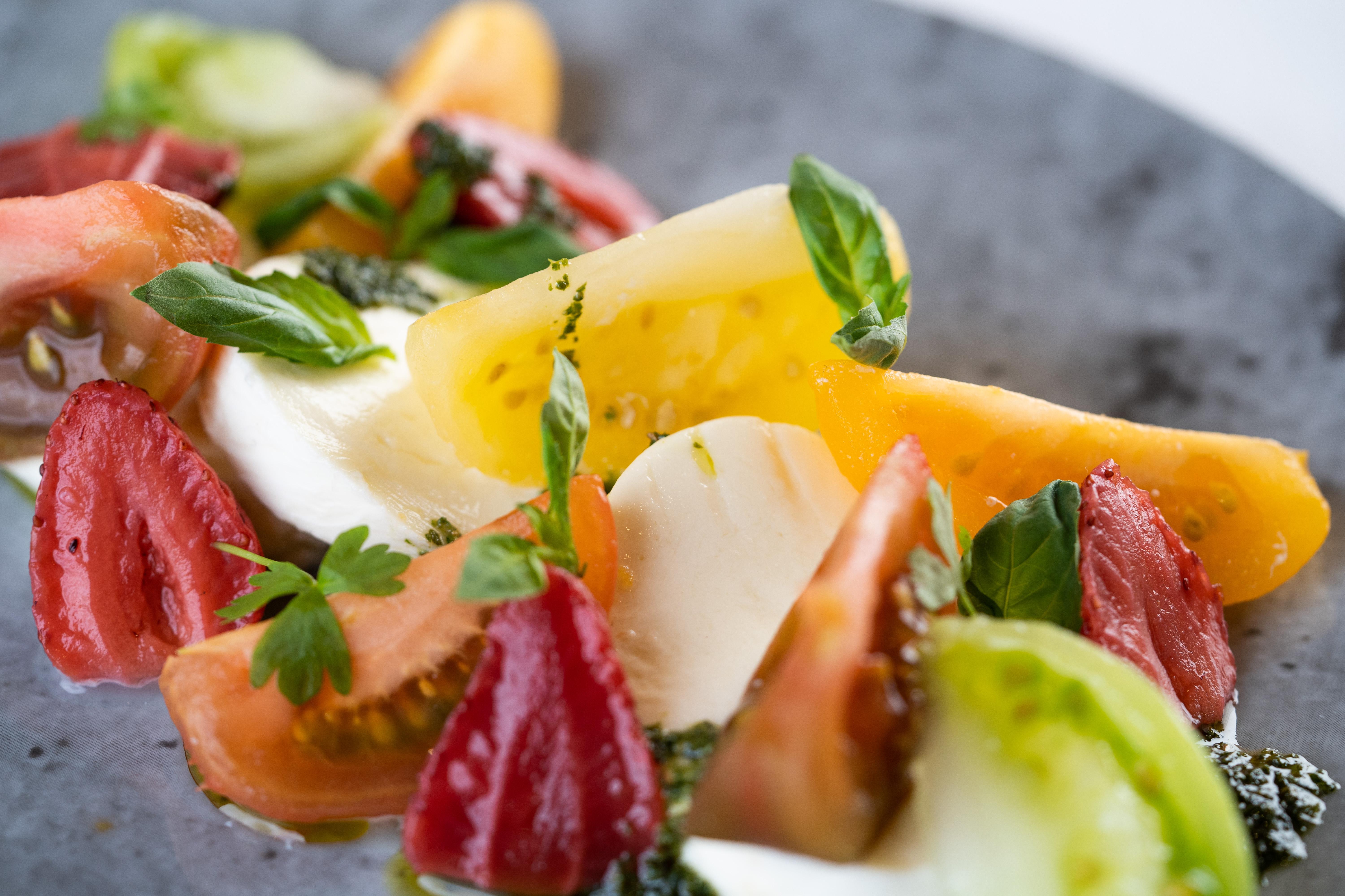 ザ フィッツウィリアム ホテル ベルファスト エクステリア 写真 The photo shows a vibrant salad featuring slices of various tomatoes, including red, yellow, and green varieties. The tomatoes are paired with fresh mozzarella cheese and garnished with basil leaves. The dish is presented on a round, dark plate, high