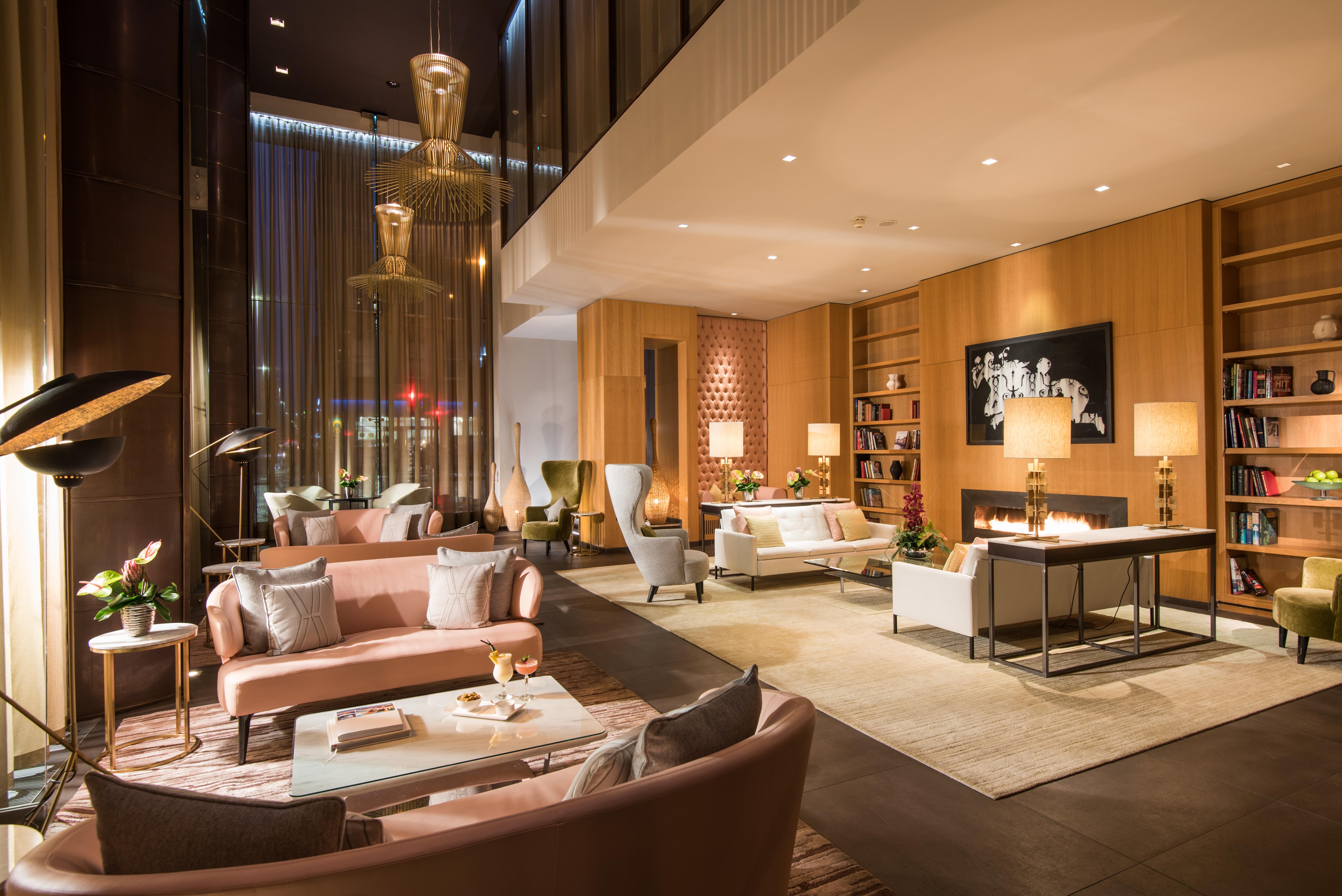 ザ フィッツウィリアム ホテル ベルファスト エクステリア 写真 The photo shows a modern and elegant lobby or lounge area. The space features a mix of contemporary and cozy furniture, including light-colored sofas and armchairs arranged around small tables. There are decorative elements like vases with flowers, a